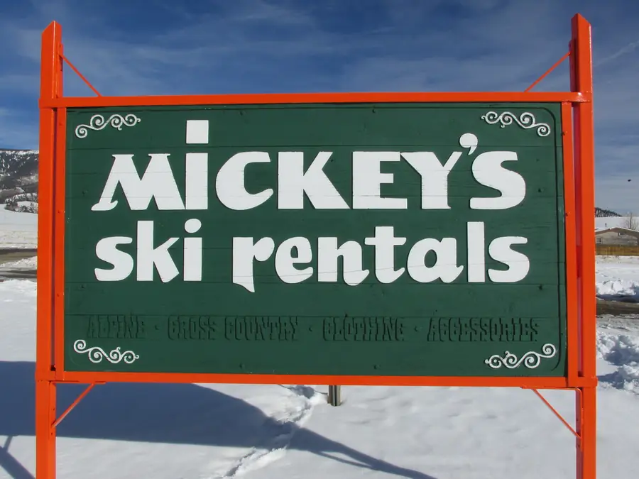 The green Mickey's Ski Rentals sign with orange posts